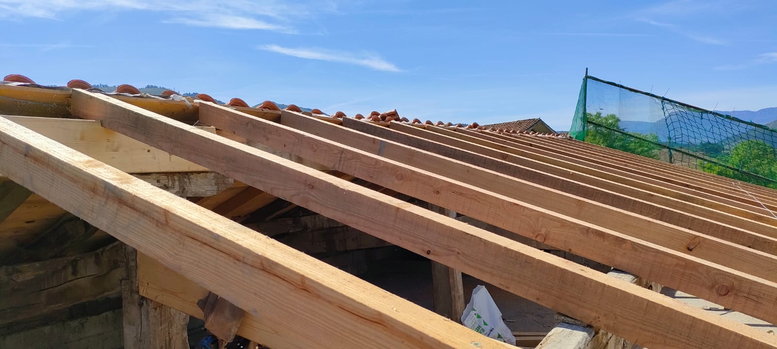 Colocación de cabios, frentes y tabla canteada en madera de alerce, tablero hidrófugo machihembrado antihumedad, doble rastrel, lámina impermeable y transpirable y recubrimiento con teja cerámica mixta.